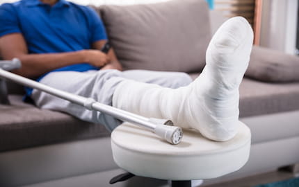 La jambe bandée et la béquille d'un salarié blessé dans le cadre d'un accident du travail.