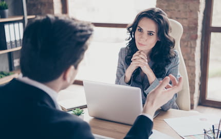 Un chef d’entreprise qui explique ses besoins de recrutement à la conseillère de son agence d’intérim.