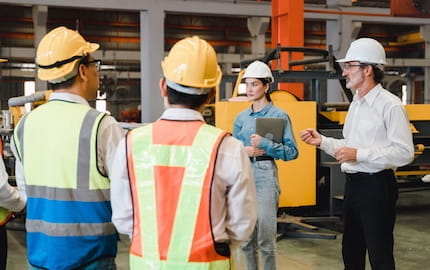 Un chef d’entreprise parle devant plusieurs salariés, et fait preuve d’assertivité.